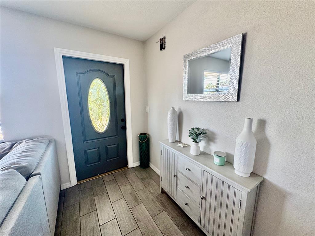 An entryway features a dark blue front door, wood-look tile flooring, and a gray console table — 118 ROTONDA CIRCLE, ROTONDA WEST, FL