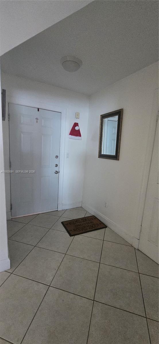 The entryway features white walls, a tiled floor, a front door, and a wall mirror — 18900 NE 14th Ave # D105, Miami FL 33179, MIAMI, FL