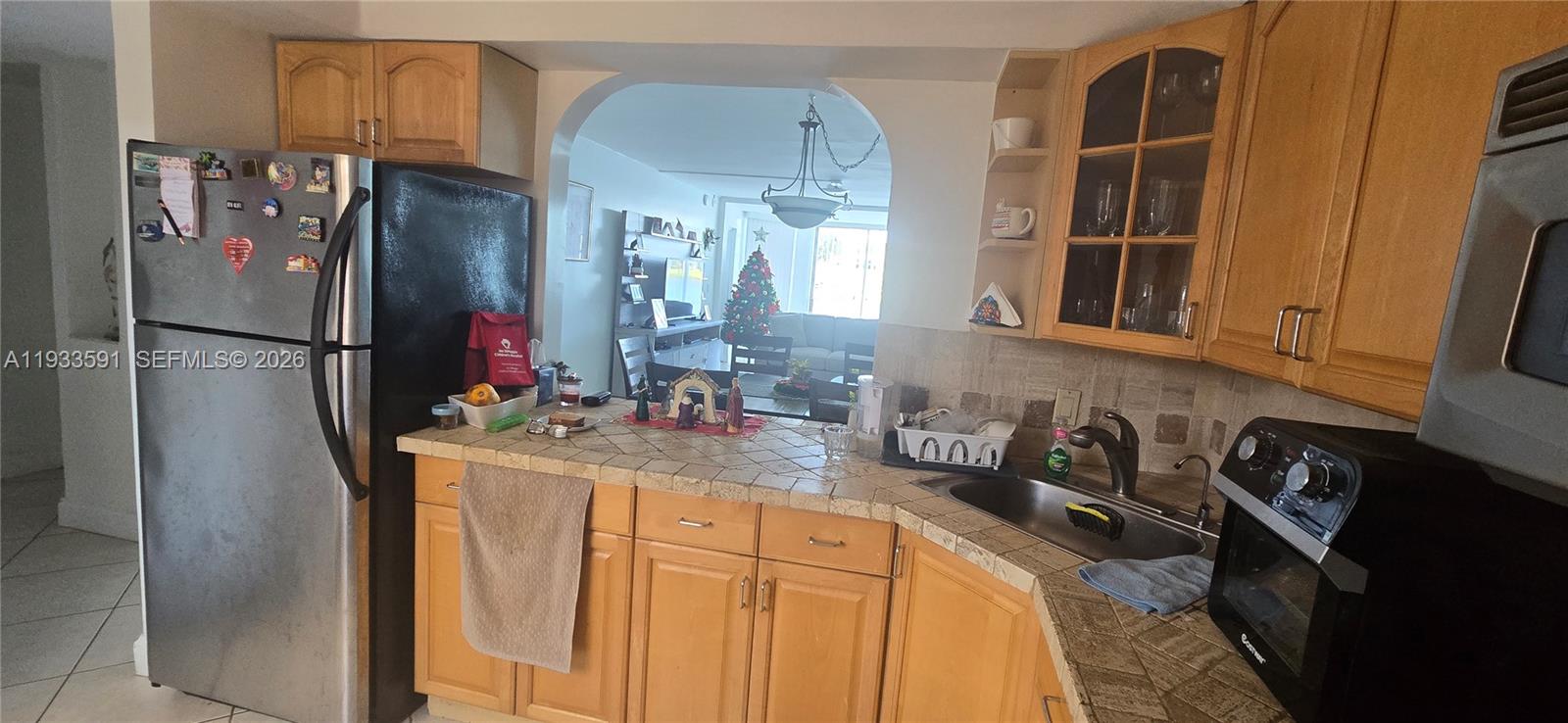 A kitchen with wood cabinets, tiled countertops, and a stainless steel refrigerator — 18900 NE 14th Ave # D105, Miami FL 33179, MIAMI, FL