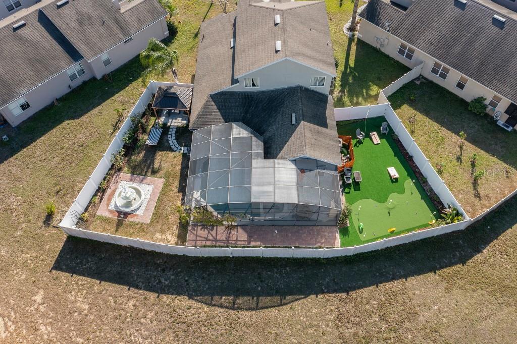 An aerial view shows a fenced backyard with a pool enclosure, putting green, and fountain — 403 CORVINA DRIVE, DAVENPORT, FL
