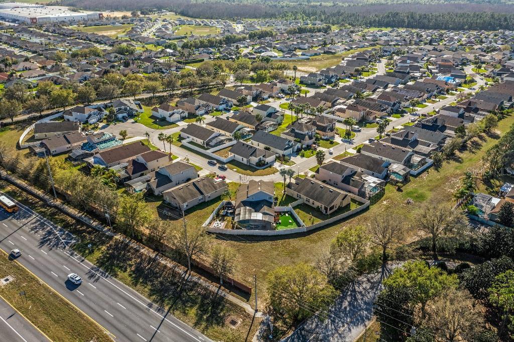 Aerial view of a suburban residential neighborhood with houses, streets, and a nearby highway — 403 CORVINA DRIVE, DAVENPORT, FL