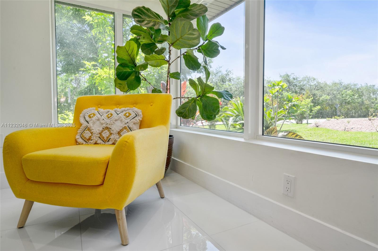 A bright yellow armchair sits on a white tiled floor next to a large window — 7544 SW 78th Ter, Miami FL 33143, MIAMI, FL