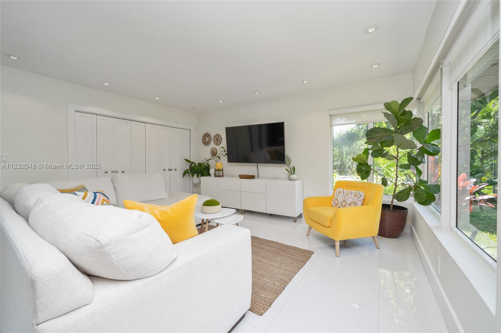 A bright living room features a white sofa, yellow armchair, television, and large windows — 7544 SW 78th Ter, Miami FL 33143, MIAMI, FL