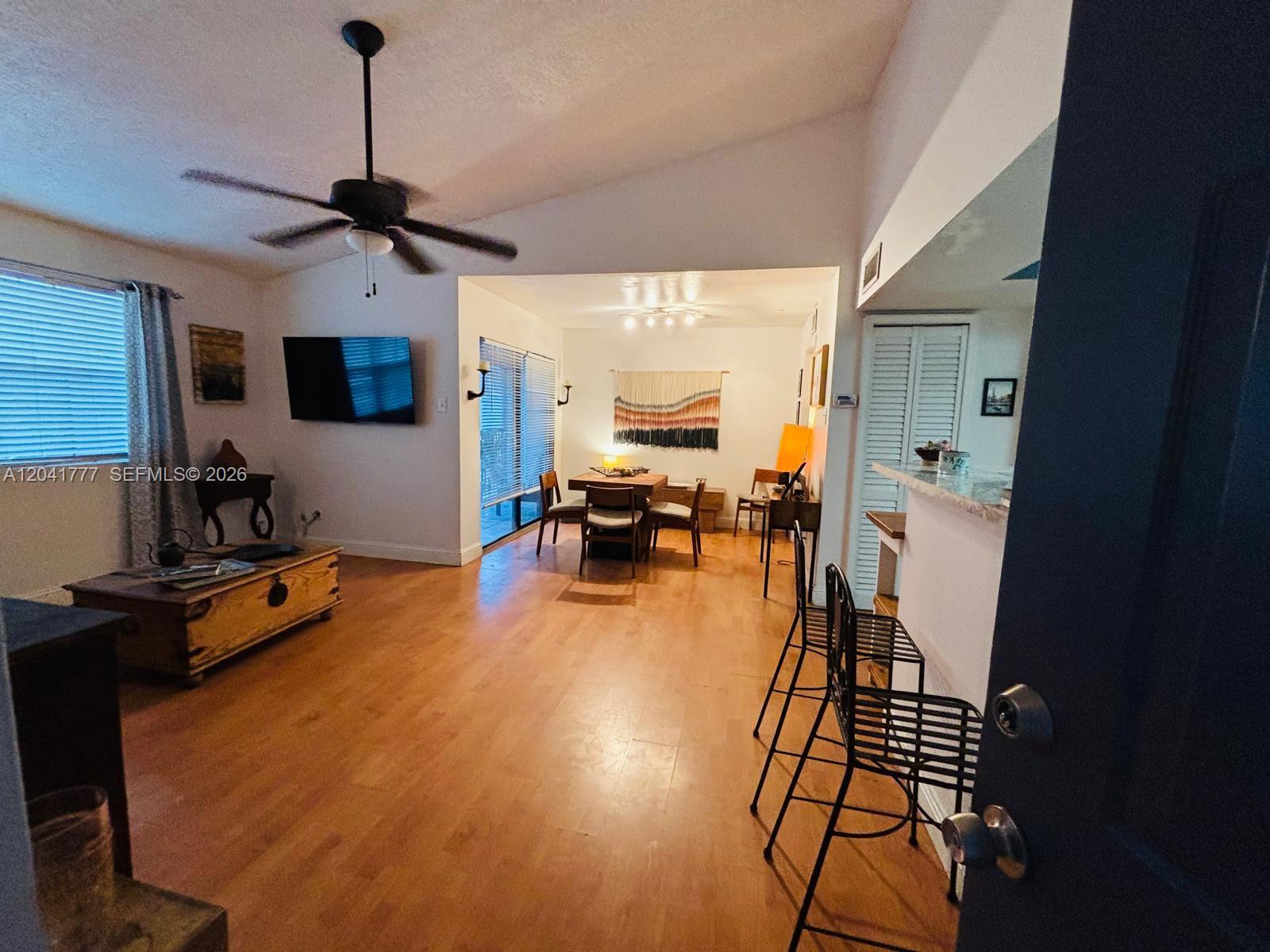 An open-concept living and dining area features wood flooring, a ceiling fan, and bar seating — 15050 SW 103rd Ter # 7202, Miami FL 33196, MIAMI, FL