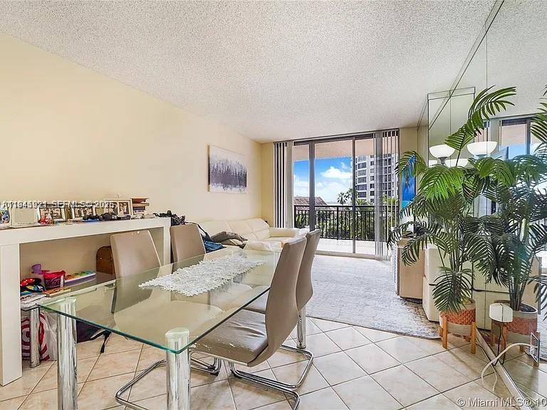 A dining area with a glass table, beige chairs, and a balcony overlooking city buildings — 540 Brickell Key Dr # 603, Miami FL 33131, MIAMI, FL