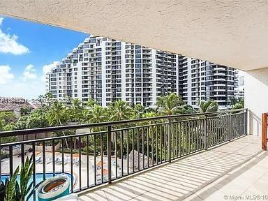 A balcony with a metal railing overlooks a swimming pool and a large apartment building — 540 Brickell Key Dr # 603, Miami FL 33131, MIAMI, FL
