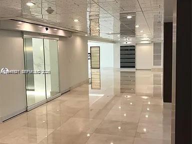 A modern hallway features polished tile floors, a drop ceiling, and glass elevator doors — 540 Brickell Key Dr # 603, Miami FL 33131, MIAMI, FL