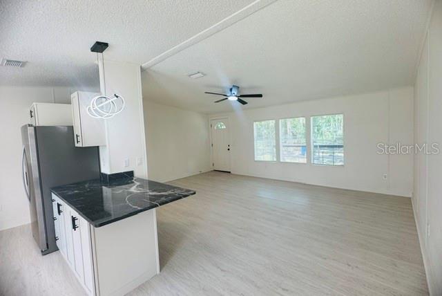 A kitchen with a black marble-topped island opens into a bright, spacious living area — 11898 SW 36TH WAY, WEBSTER, FL