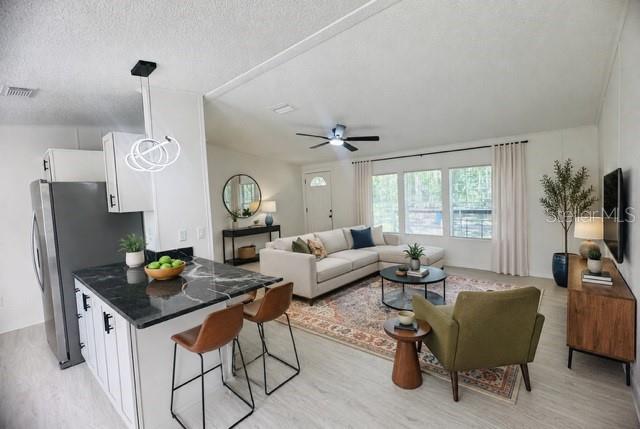 An open-concept living room and kitchen feature a marble-topped island and neutral-toned furniture — 11898 SW 36TH WAY, WEBSTER, FL