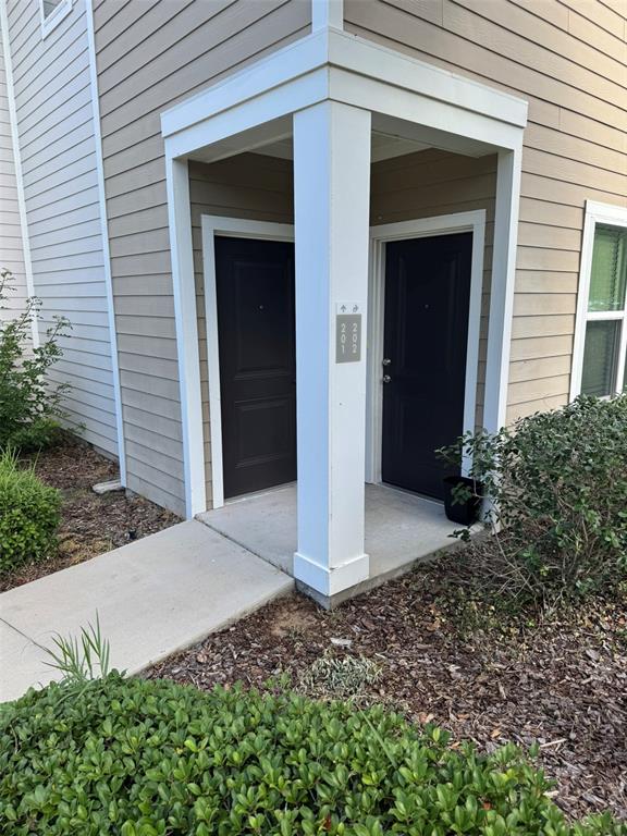The exterior view shows two dark apartment doors under a covered entryway with beige siding — 2420 ANN ROU ROAD UNIT 201, TAVARES, FL