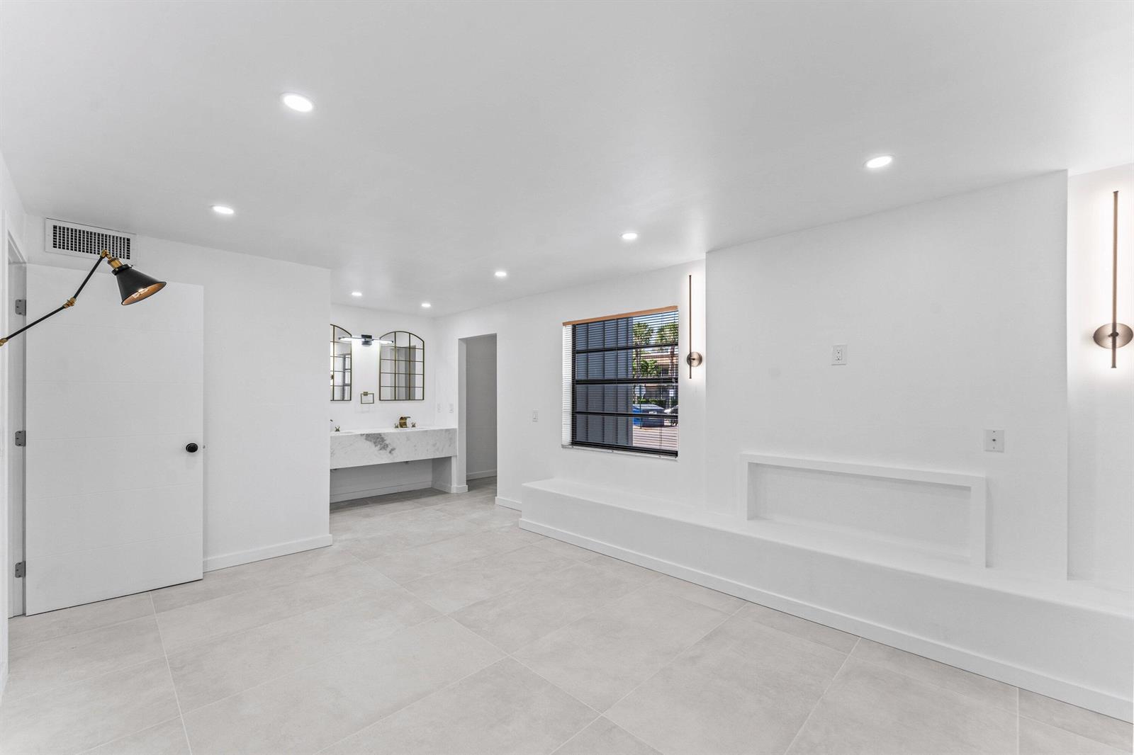 A minimalist room with white walls, light tile flooring, a marble vanity, and recessed shelving — 551 Piedmont L, Delray Beach FL 33484, DELRAY BEACH, FL