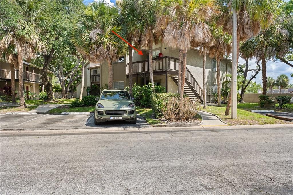 A two-story apartment building with a balcony, exterior stairs, and a parked SUV in front — 6345 NEWTOWN CIRCLE UNIT 45B2, TAMPA, FL