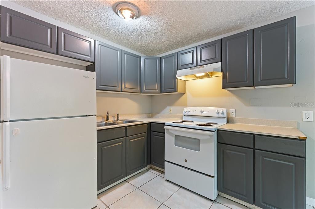 A kitchen with gray cabinets, white appliances, and light-colored tile flooring — 6345 NEWTOWN CIRCLE UNIT 45B2, TAMPA, FL