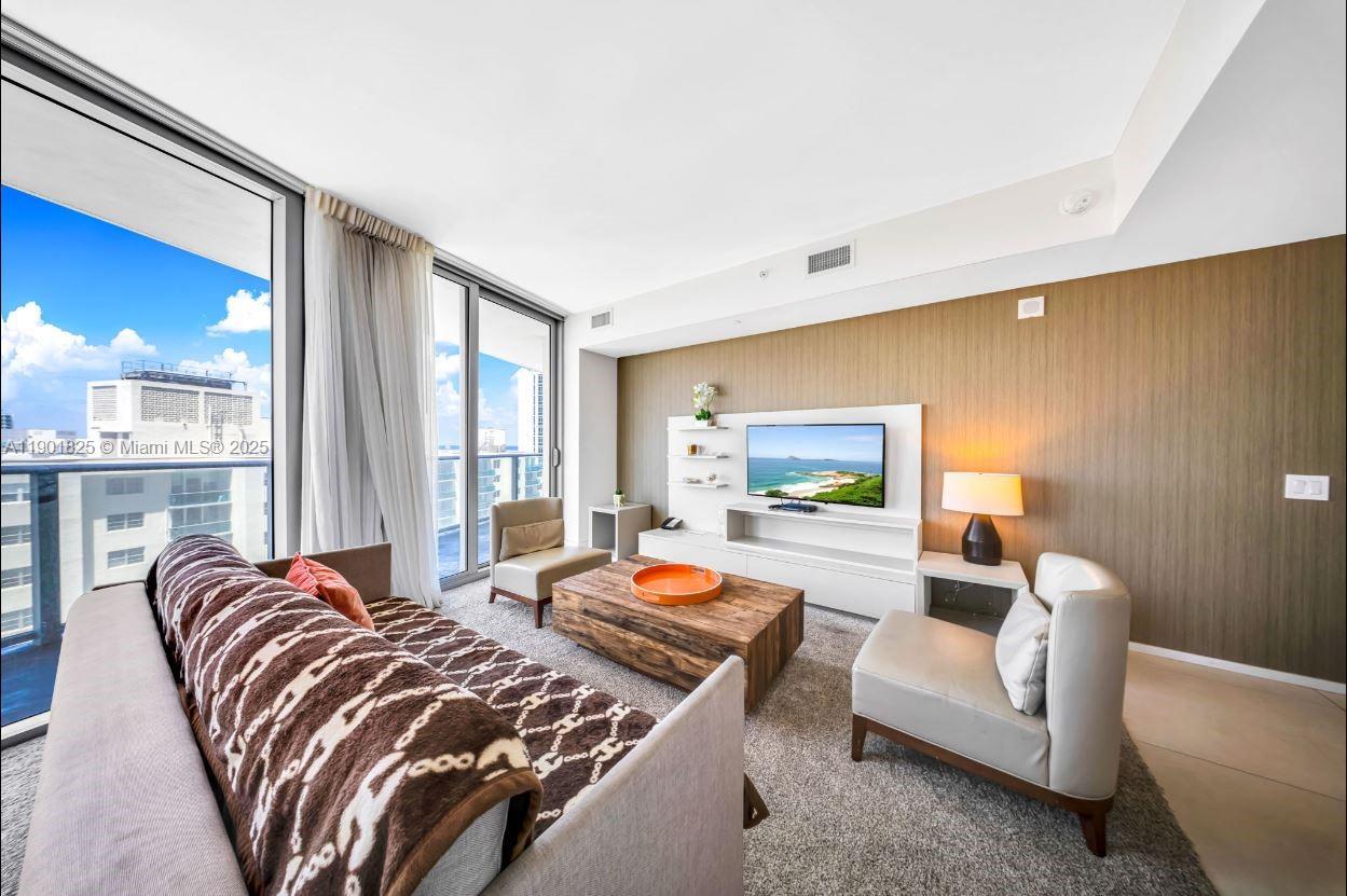 A living room features a brown patterned throw, wooden coffee table, and floor-to-ceiling windows — 4111 S Ocean Dr # 1212, Hollywood FL 33019, HOLLYWOOD, FL