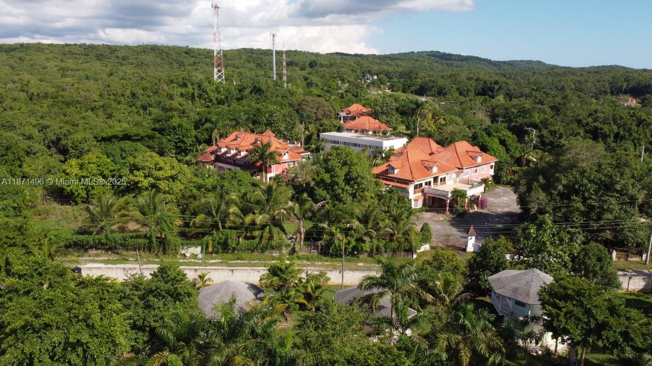 An aerial view shows large multi-story houses with red tile roofs surrounded by dense trees — Summerset Negril, Jamaica, NA, NA