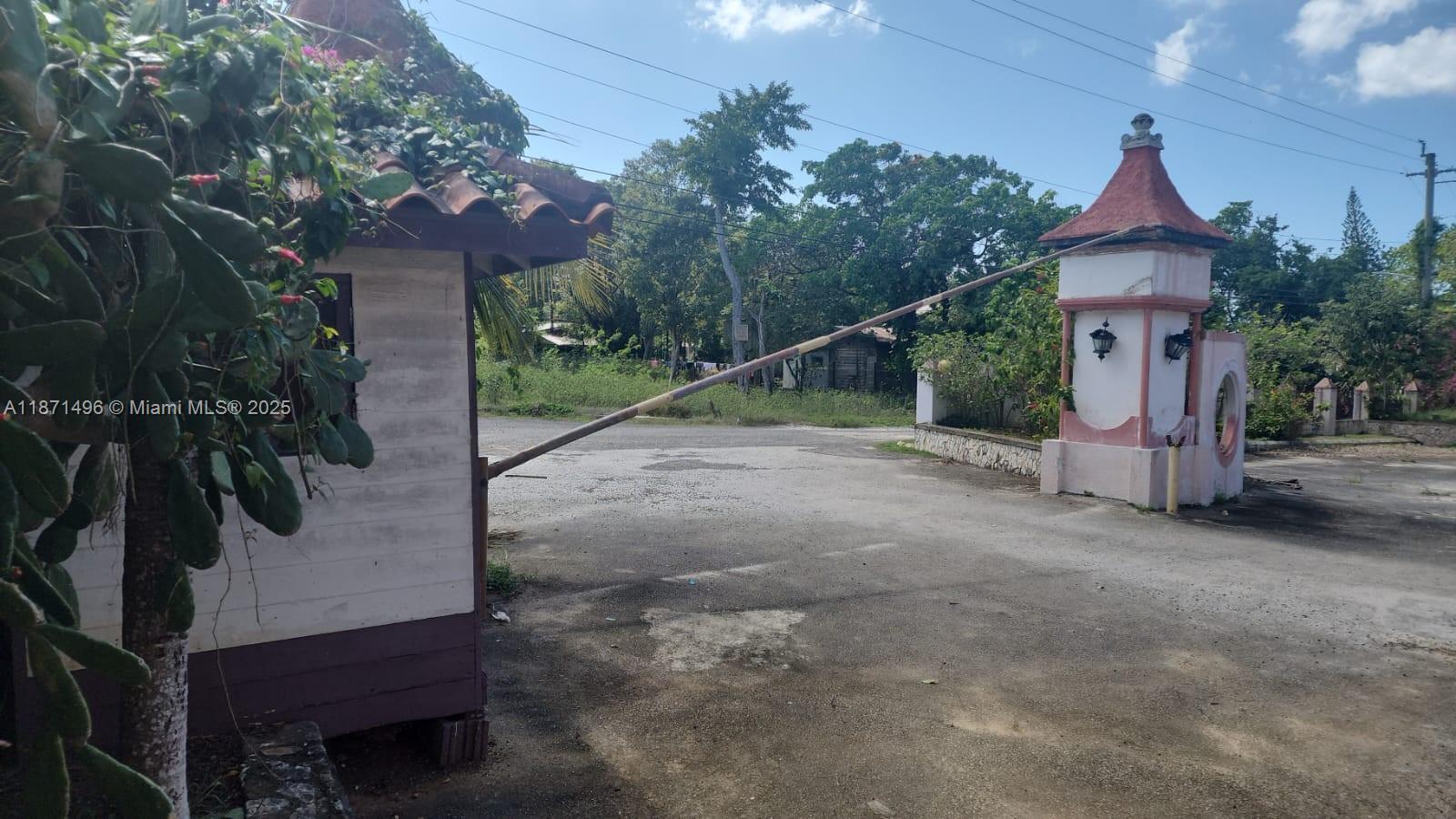 A gated entrance features a small guardhouse and a decorative pillar with a barrier arm — Summerset Negril, Jamaica, NA, NA