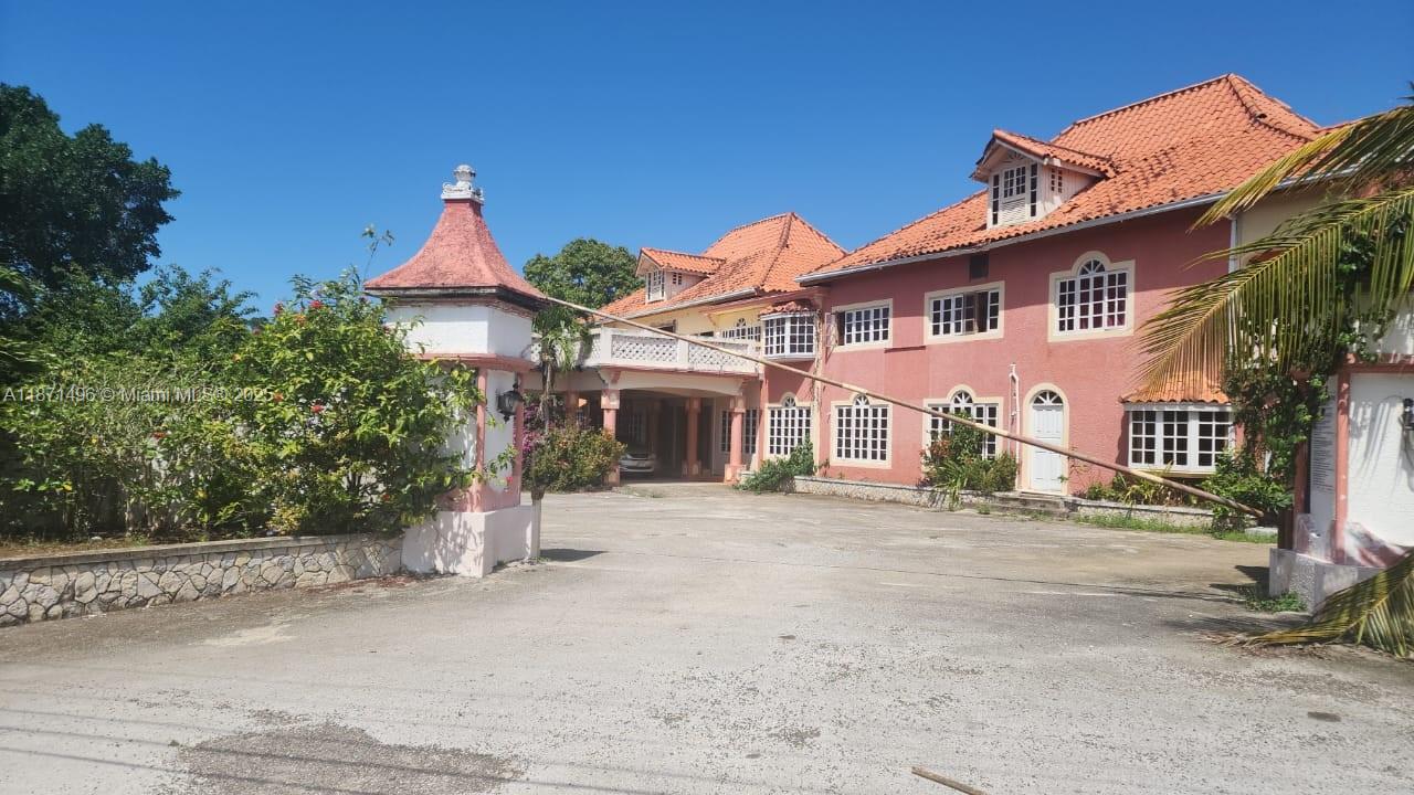A large, multi-story pink house with a tiled roof and a gated driveway entrance — Summerset Negril, Jamaica, NA, NA