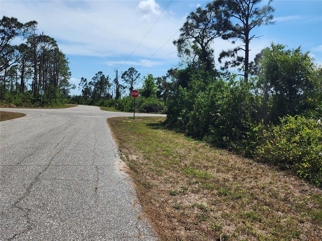 An asphalt road leads to a T-intersection marked by a stop sign in a wooded area — 12282 APPLEBERG CIRCLE, PORT CHARLOTTE, FL