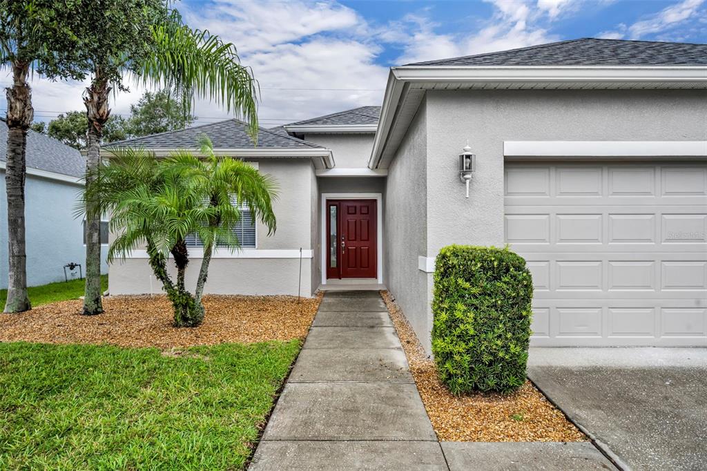 The exterior of a single-story house features a red front door and a garage — 2628 BALFORN TOWER WAY, WINTER GARDEN, FL