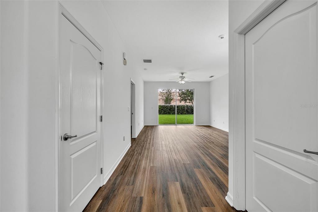 A hallway with wood-look flooring leads to a living area with sliding glass doors — 2628 BALFORN TOWER WAY, WINTER GARDEN, FL
