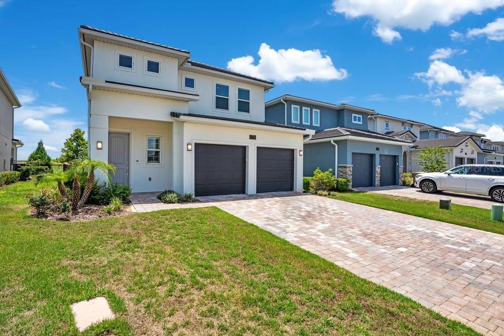 A two-story house with a two-car garage and a paved driveway under a blue sky — 15738 VETTA DRIVE, BELLA COLLINA, FL