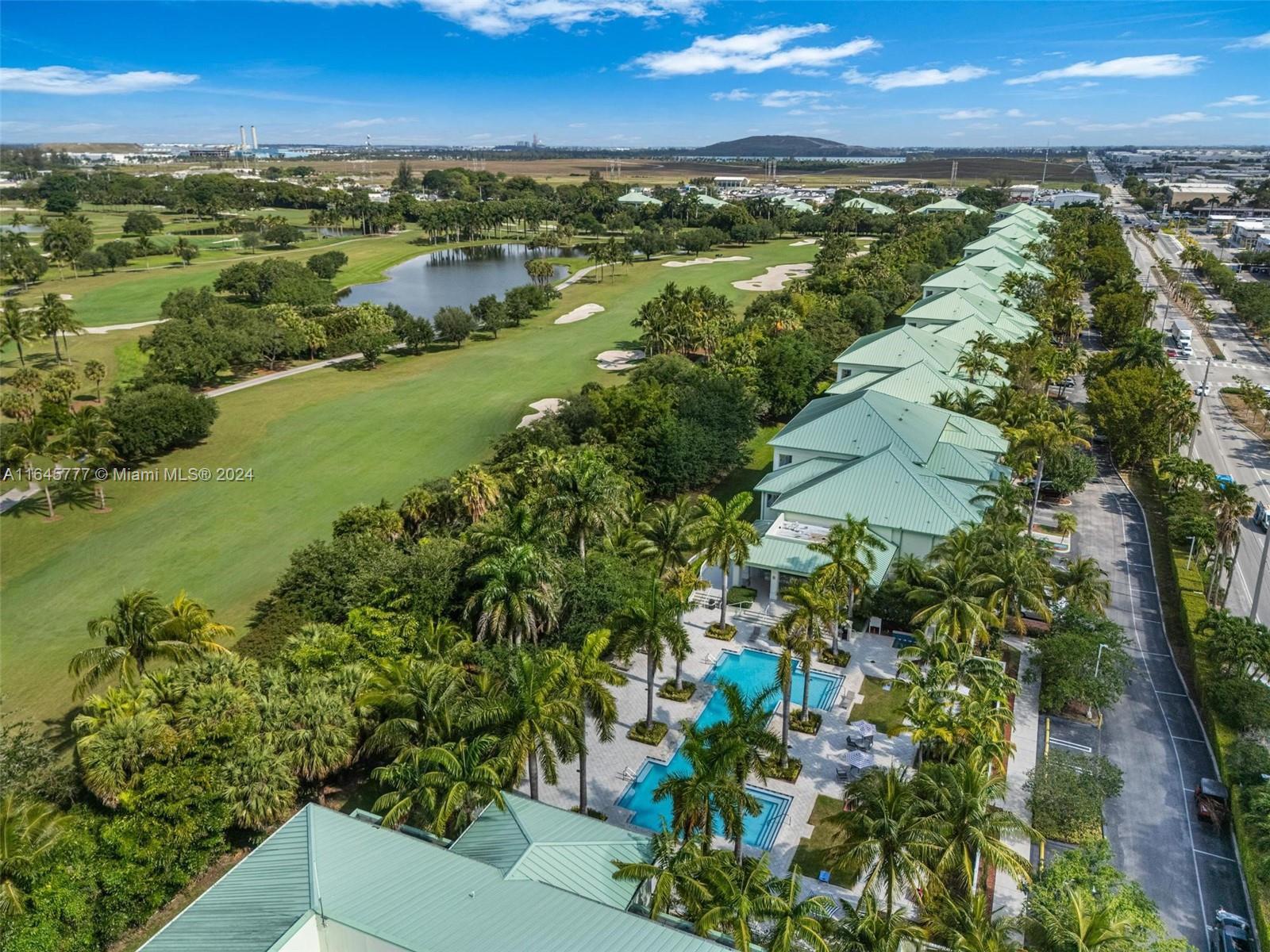An aerial view shows a row of townhouses with green roofs beside a golf course — 5300 NW 87th Ave # 1308, Doral FL 33178, DORAL, FL