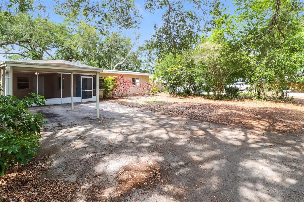 A single-story house with a screened-in porch and a cracked concrete driveway under trees — 1619 EDNA AVENUE, LARGO, FL