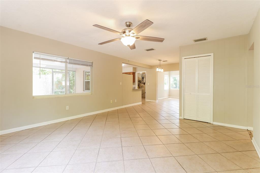 An open living area with beige tile flooring, a ceiling fan, and a white closet — 1619 EDNA AVENUE, LARGO, FL