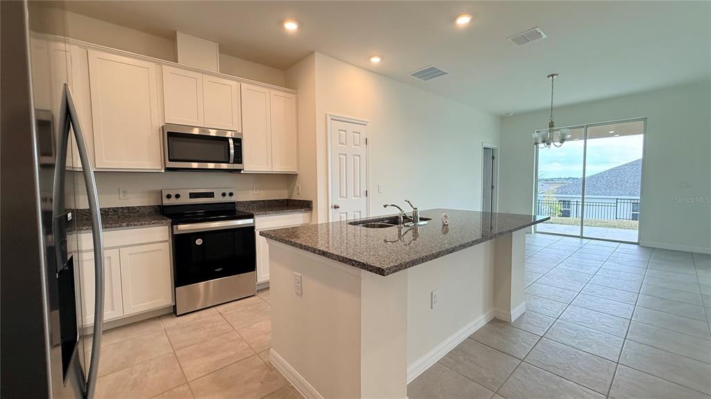 A kitchen with white cabinets, granite countertops, stainless steel appliances, and a central island — 2334 SELENIA STREET, LAKE ALFRED, FL