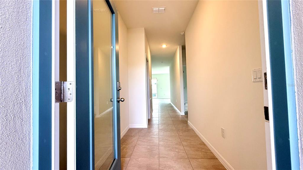 A view through an open blue front door into a tiled hallway with light walls — 2334 SELENIA STREET, LAKE ALFRED, FL