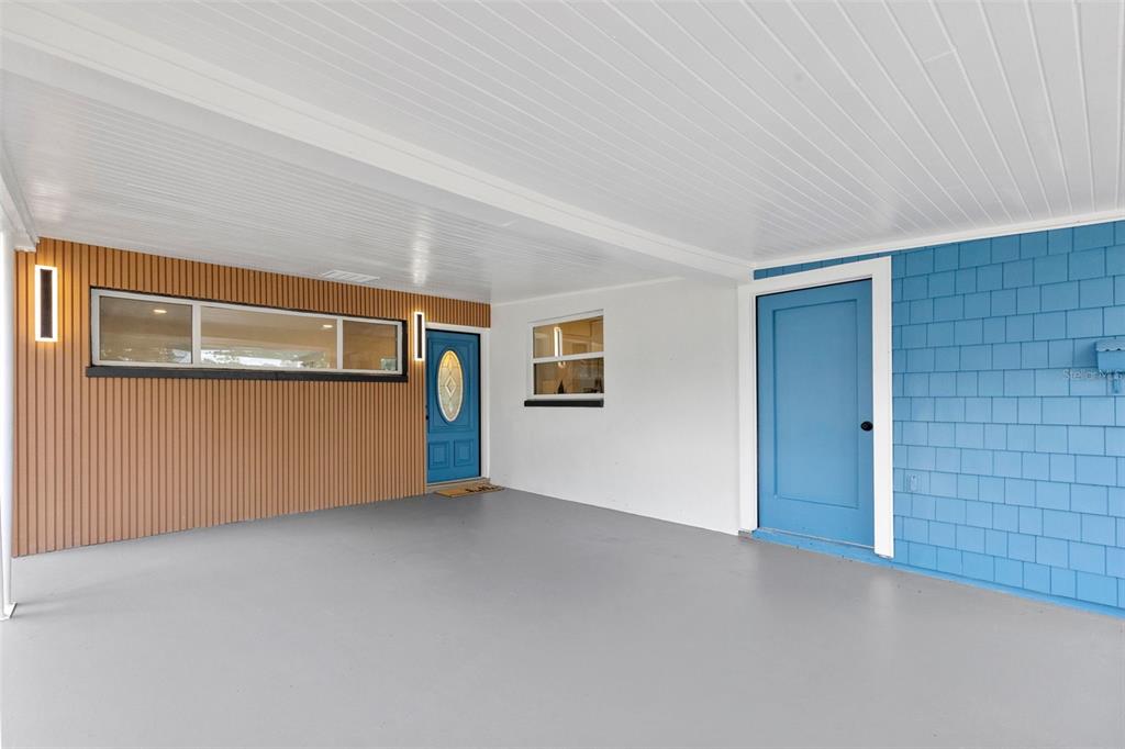A blue house with a carport, a concrete driveway, and a palm tree in the yard — 10221 N FLEETWOOD DRIVE, TAMPA, FL