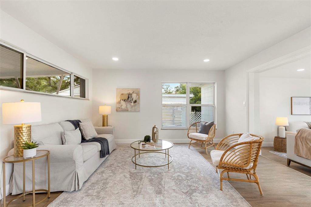 A dining area with a round wooden table sits before a living room and kitchen — 10221 N FLEETWOOD DRIVE, TAMPA, FL