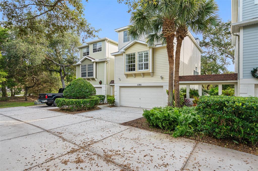 A two-story yellow house with a two-car garage and a paved driveway — 1381 CURLEW ROAD, DUNEDIN, FL