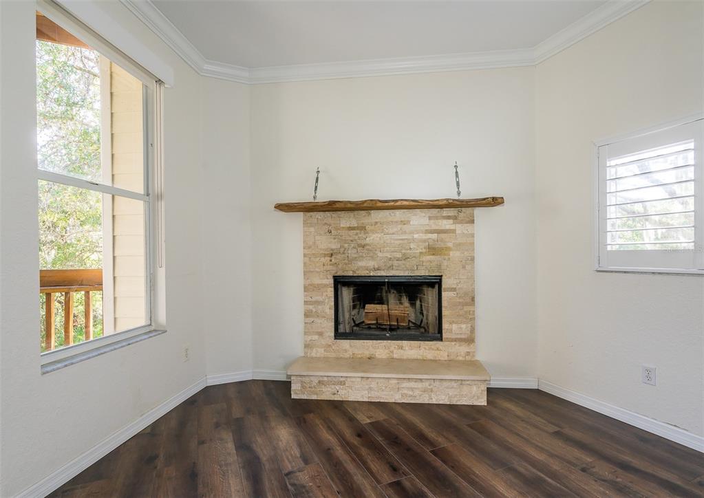 A room with dark wood flooring, white walls, and a stone fireplace with a wood mantel — 1381 CURLEW ROAD, DUNEDIN, FL