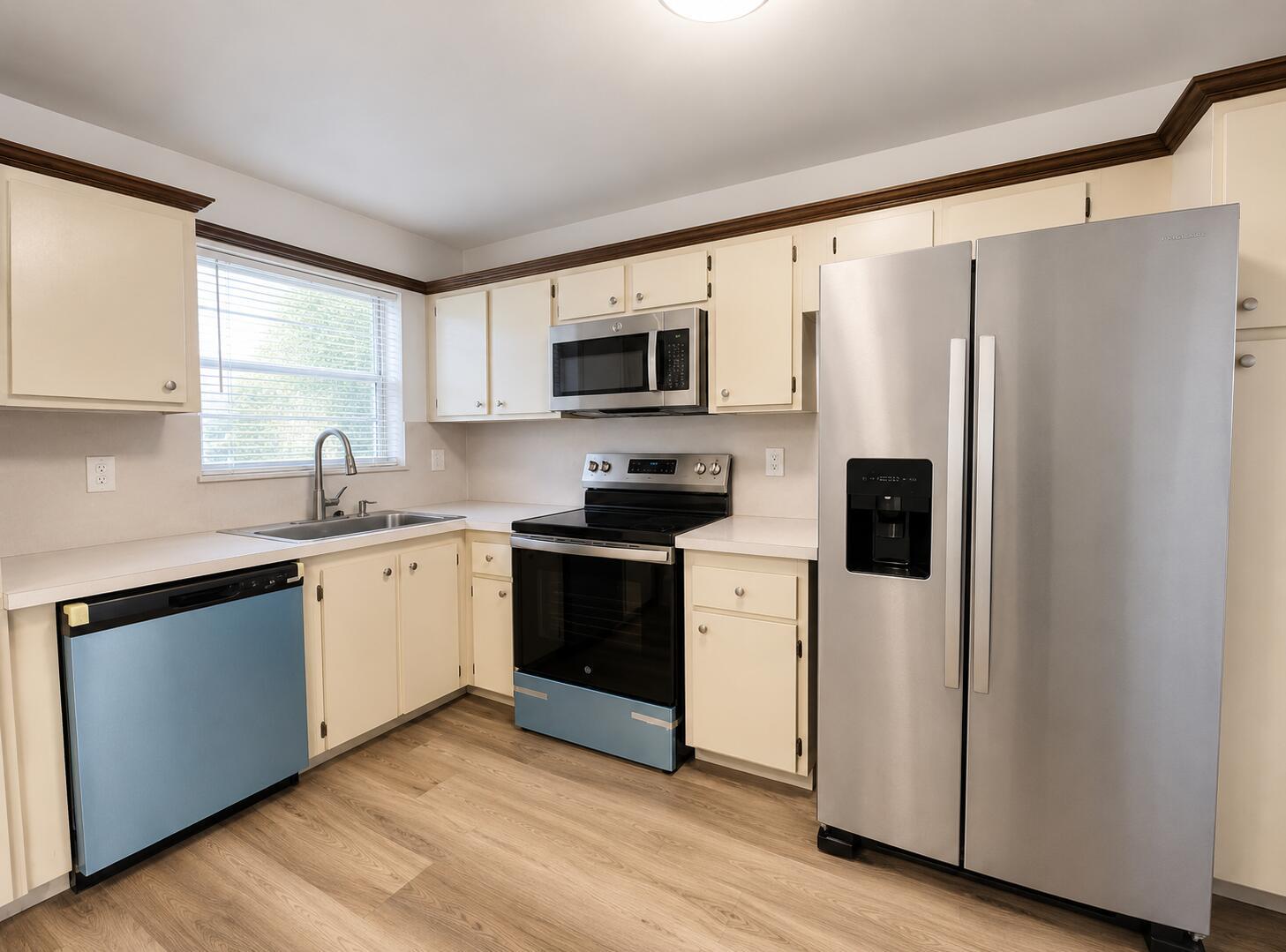 A kitchen features cream cabinets, stainless steel appliances, a blue dishwasher, and light wood flooring — 601 S State Rd 7 # 2h, Margate FL 33068, MARGATE, FL