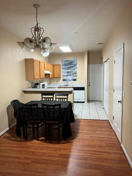 A dining area with a chandelier and table sits before an open kitchen with wood cabinets — 4415 SW 34TH STREET UNIT 608, GAINESVILLE, FL