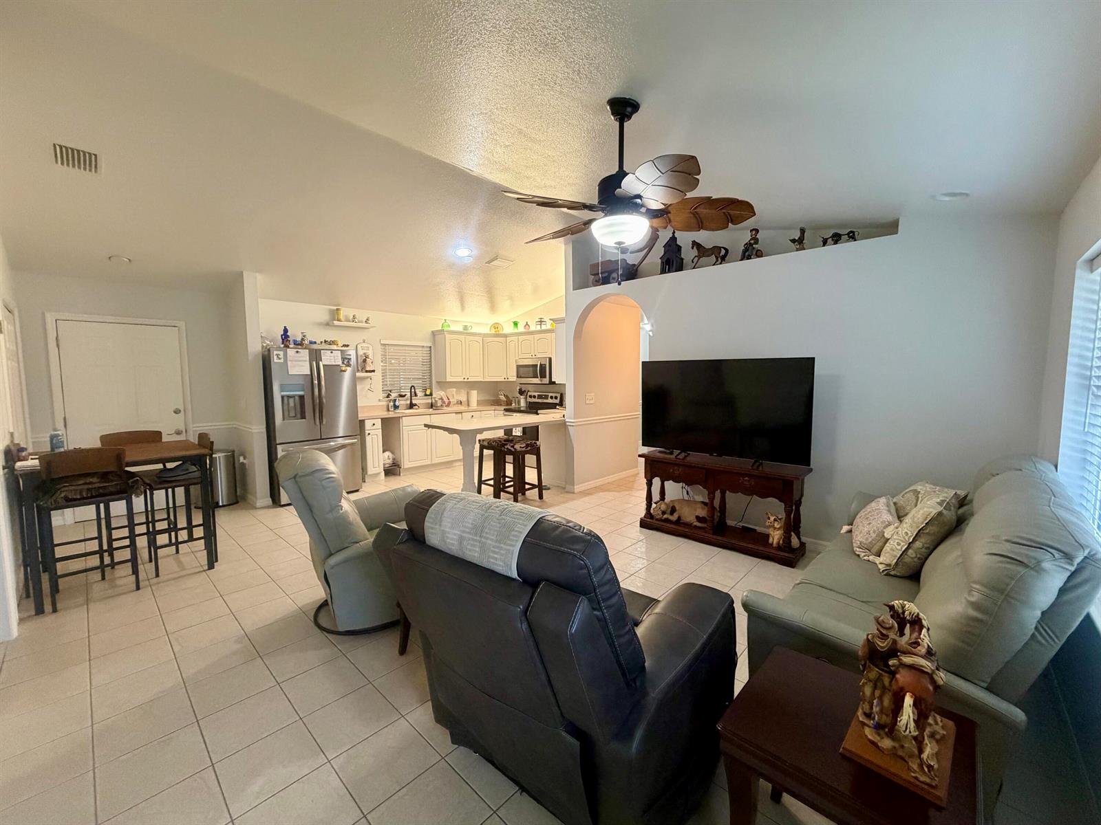 An open-concept living room and kitchen with tile flooring, a ceiling fan, and a television — 7823 SW 9th Street, Okeechobee FL 34974, OKEECHOBEE, FL