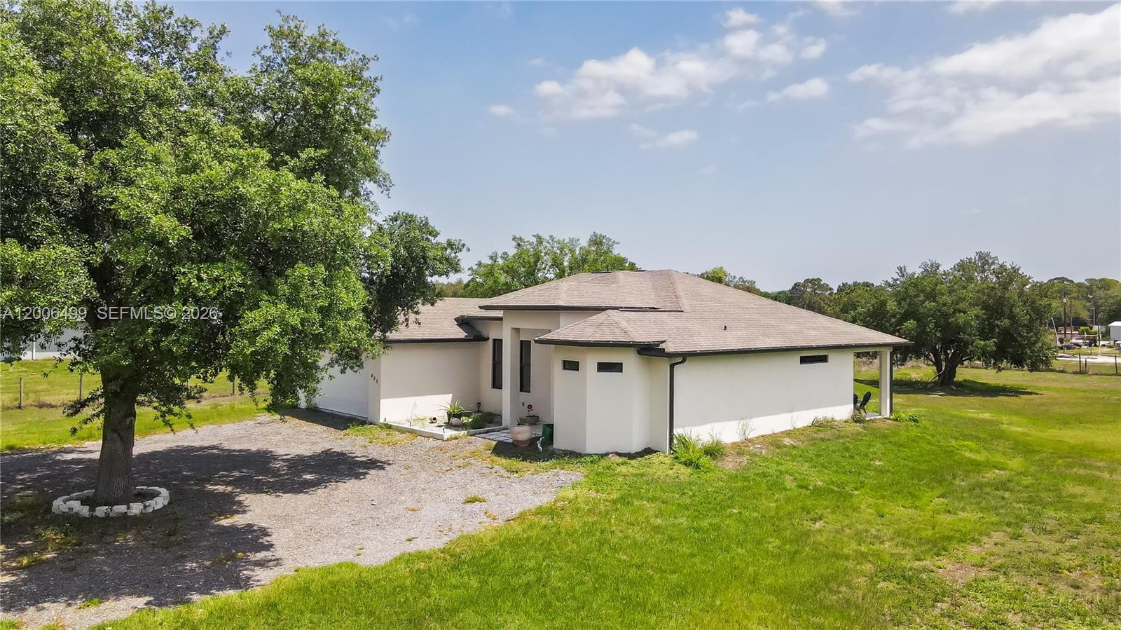 An exterior view of a single-story house with a gravel driveway and surrounding lawn — 655 N Olivo ST, Clewiston FL 33440, CLEWISTON, FL