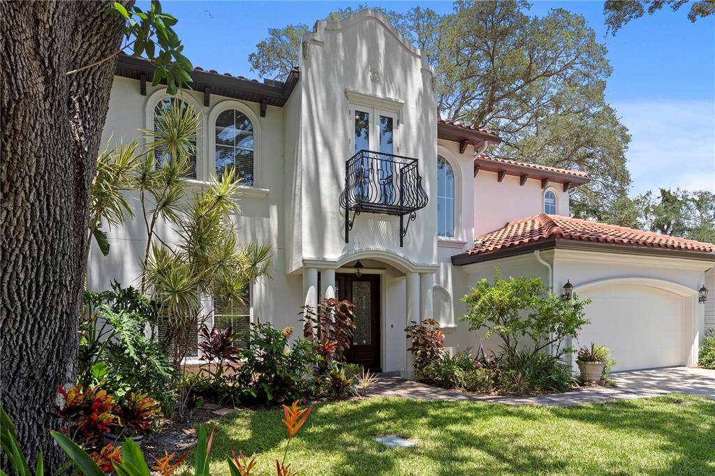 A two-story stucco house features a tiled roof, a wrought-iron balcony, and a front garage — 3911 W DALE AVENUE, TAMPA, FL