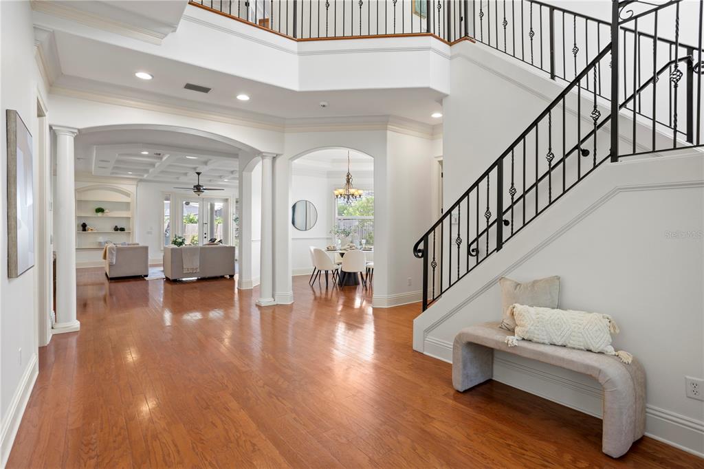 A bright foyer features hardwood floors, a staircase with iron railings, and arched room entries — 3911 W DALE AVENUE, TAMPA, FL