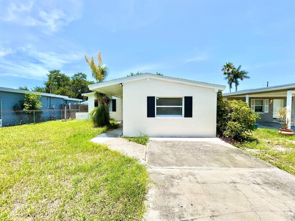 A single-story house with a concrete driveway, a small front lawn, and black window shutters — 673 59TH STREET S, ST PETERSBURG, FL