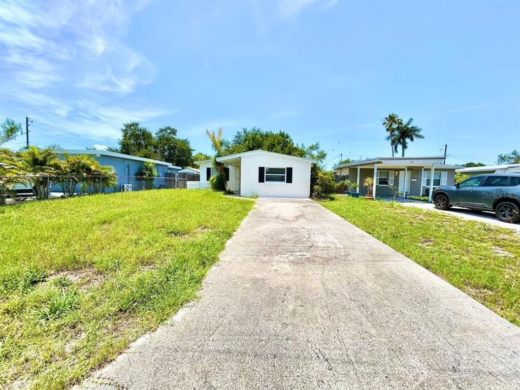 A white single-story house with a concrete driveway and a large front lawn — 673 59TH STREET S, ST PETERSBURG, FL