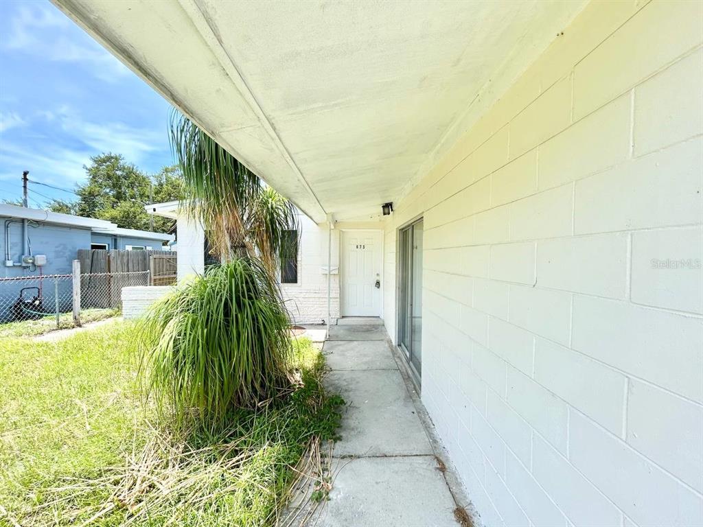 A concrete walkway leads to a white front door under a covered porch — 673 59TH STREET S, ST PETERSBURG, FL