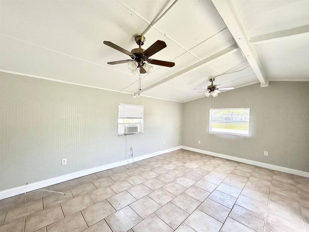 An empty room features tiled floors, white walls, and two ceiling fans — 673 59TH STREET S, ST PETERSBURG, FL