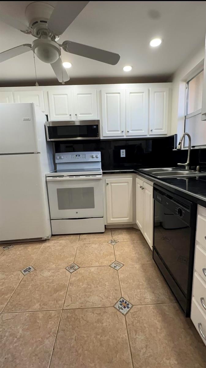 A kitchen features white cabinets, a black backsplash, tile flooring, and a mix of appliances — 6770 Royal Palm Boulevard # 207l, Margate FL 33063, MARGATE, FL