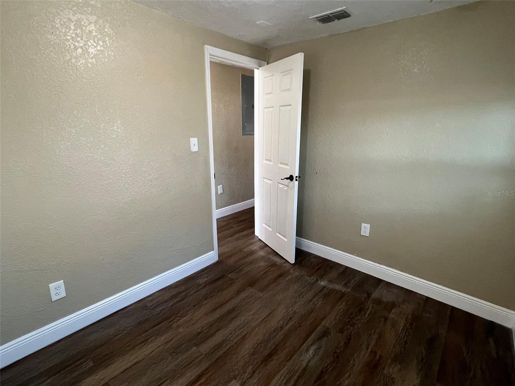 An empty room features tan walls, white trim, and dark wood-look flooring — 1307 W KALEY AVENUE, ORLANDO, FL