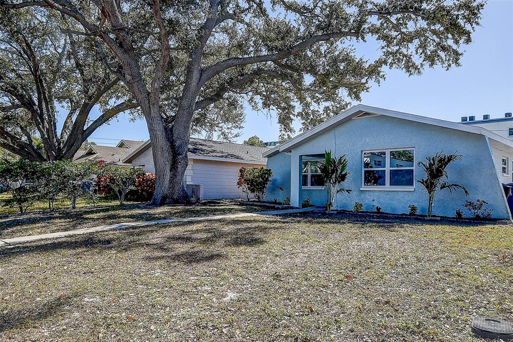 A light blue single-story house with a large oak tree in the front yard — 130 42ND AVENUE N, ST PETERSBURG, FL