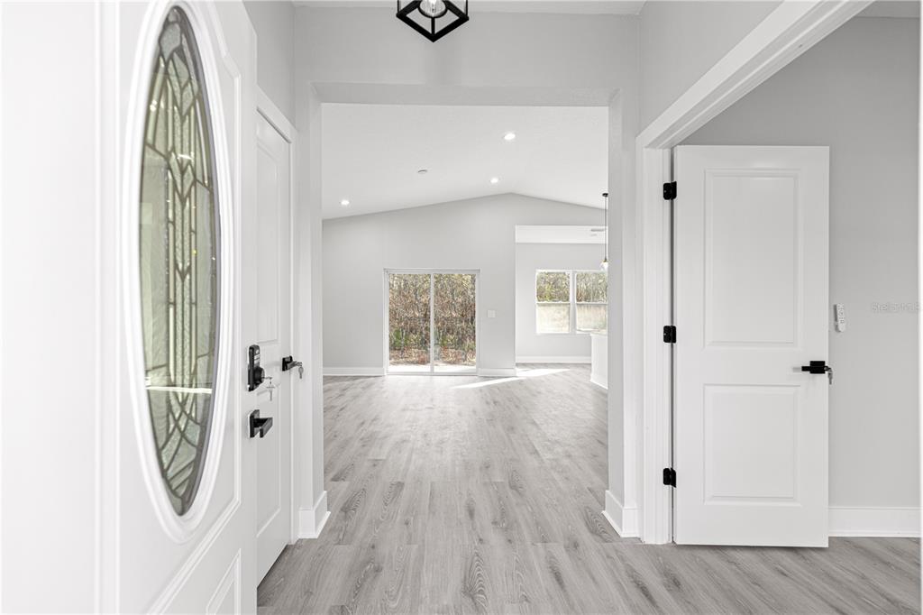 A bright entryway leads into an open-concept living area with light wood-look flooring — 8311 SW 136TH TERRACE, DUNNELLON, FL