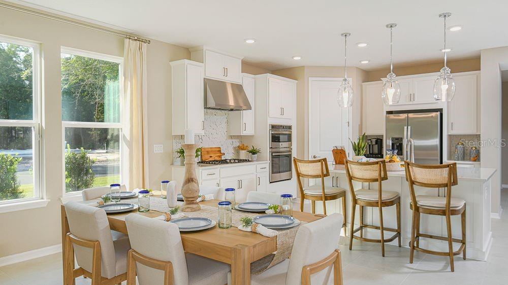 A bright kitchen and dining area features white cabinetry, stainless steel appliances, and wood furniture — 10 ARMENIA COURT, PALM COAST, FL