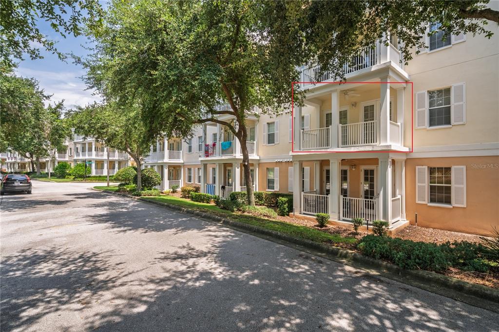 A multi-story apartment building exterior features a highlighted second-story balcony with white railings — 7503 MOURNING DOVE CIR UNIT 202, REUNION, FL